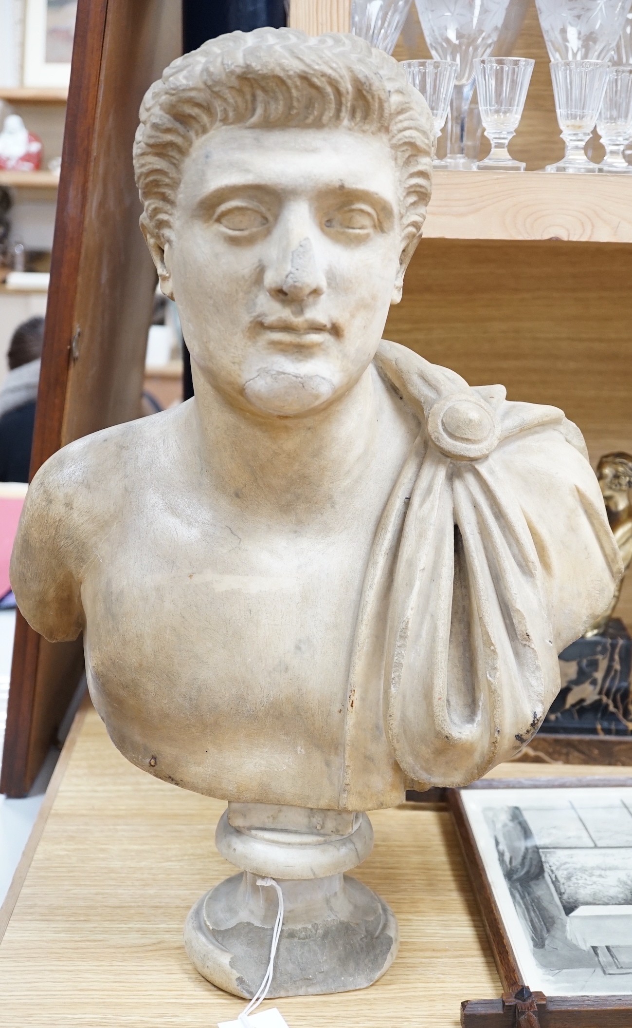After the Antique marble bust of a Roman man wearing a Chlamys with a buckle at the shoulder, later socle and repairs, 54cm tall